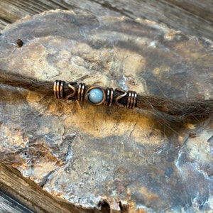 Può includere: Perle per dreadlock in rame con una pietra blu chiaro al centro.