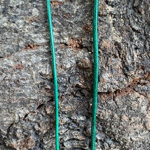 Puede incluir: Dos hebras de cord&oacute;n o cuerda verde sobre un fondo rugoso, marr&oacute;n y texturizado.