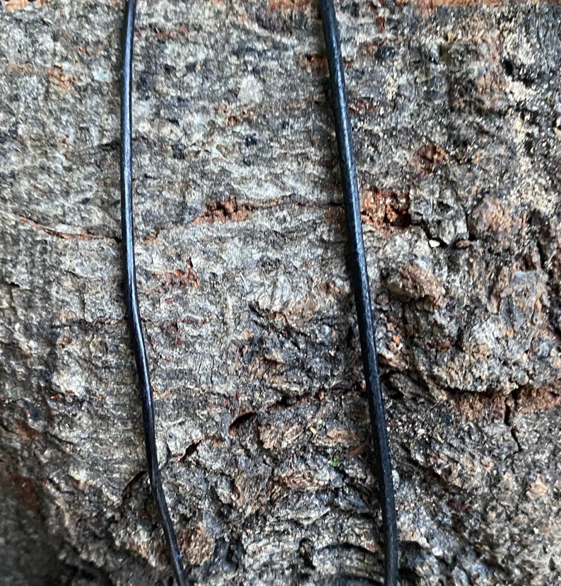Puede incluir: Primer plano de un cord&oacute;n de cuero negro sobre un fondo de madera rugoso y texturizado.