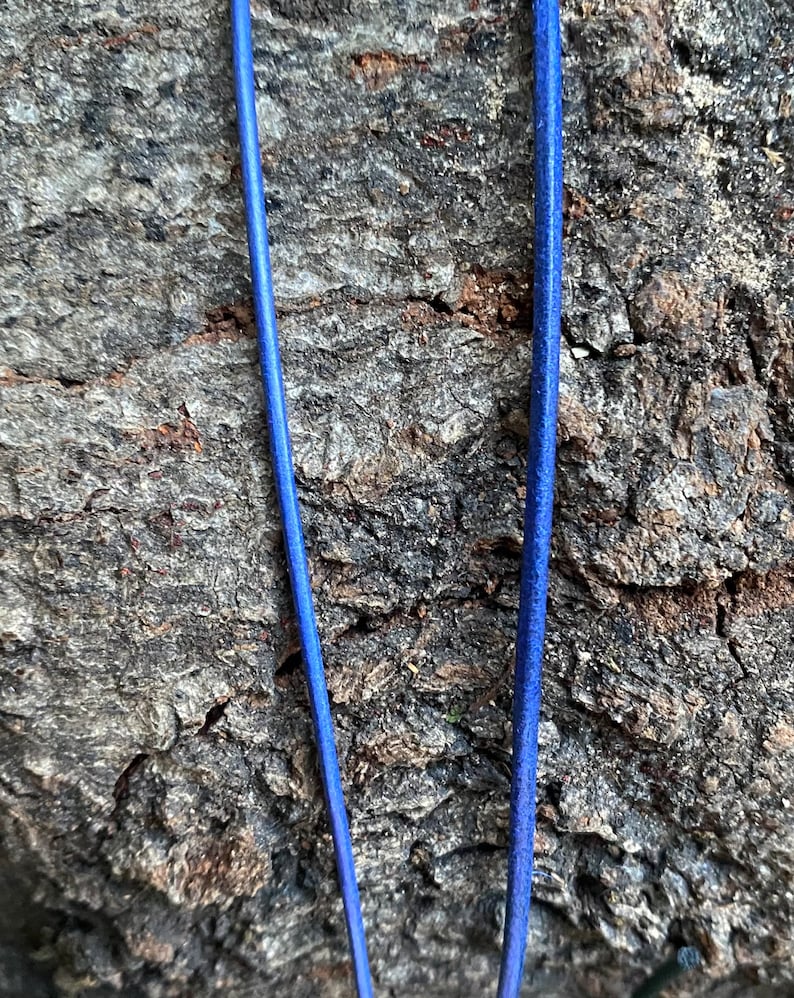 Puede incluir: Dos hebras de cord&oacute;n de cuero azul sobre un fondo rugoso, marr&oacute;n y texturizado.