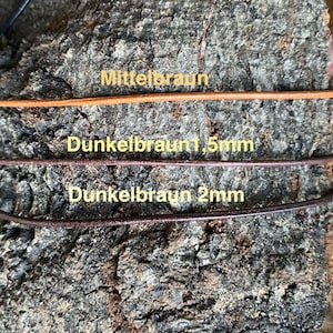 Puede incluir: Tres cordones de cuero de diferentes colores y anchos sobre una superficie de madera. Los cordones est&aacute;n etiquetados como "Mittelbraun", "Dunkelbraun 1,5 mm" y "Dunkelbraun 2 mm".