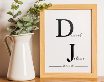 May include: A framed print with the letters "D" and "J" in black, with the names "Daniel" and "Joline" written in cursive underneath. The date "07.04.2021" is printed below the names.