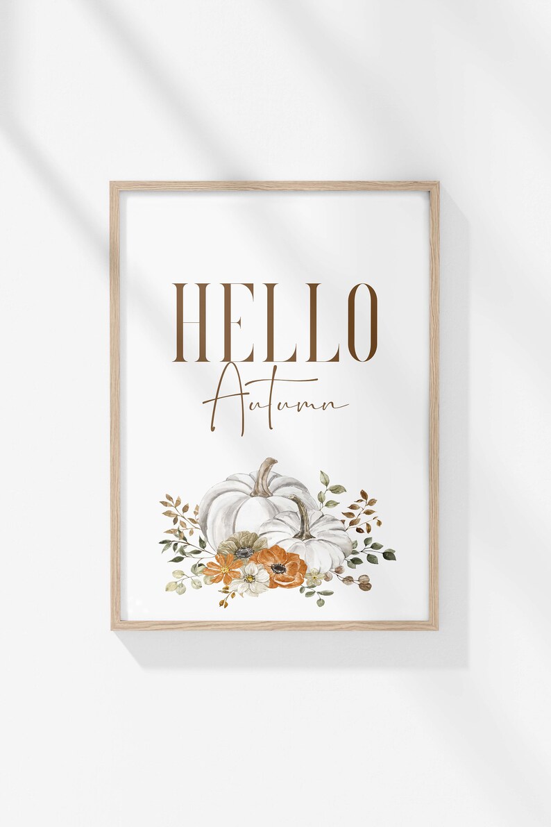 May include: A framed print with the text "HELLO Autumn" in brown lettering. The print features a watercolour illustration of two white pumpkins with orange and white flowers and green leaves.
