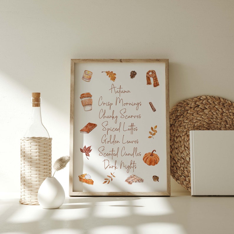 May include: A framed print with a white background and brown text that reads "Autumn, Crisp Mornings, Chunky Scarves, Spiced Lattes, Golden Leaves, Scented Candles, Dark Nights". The print features watercolor illustrations of fall-themed items, including a pumpkin, leaves, a cup of coffee, a book, a scarf, and a cinnamon stick.