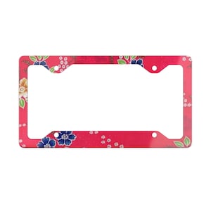 May include: A red license plate frame with a floral pattern. The frame has a white background with pink, blue, and green flowers.