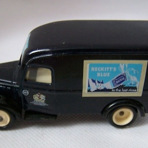 May include: A black toy delivery truck with white wheels and a side advertisement for "Reckitt's Blue" laundry detergent. The ad reads "In the last rinse".