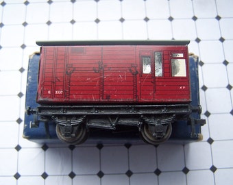May include: A red toy train carriage with black wheels and a grey roof. The carriage has a window and the text "E 2337 XP" on the side.