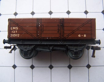 Op de afbeelding: Een bruine houten speelgoedtreinwagen met zwarte wielen en de tekst "LMS 12T 210112 6-8" gedrukt op de zijkant.