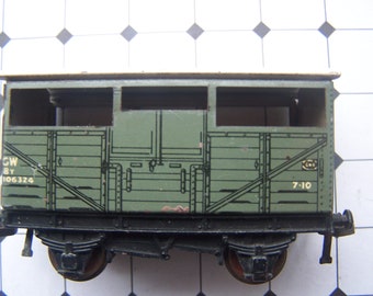 May include: A green toy train carriage with a white roof and black wheels. The carriage has the number "7-10" and the letters "CW 8T 106324" printed on the side.