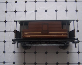 Op de afbeelding: Een bruine houten speelgoedtreinwagen met een wit dak en zwarte wielen. De wagen heeft de tekst "LMS 710026" op de zijkant.