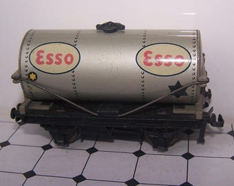 May include: A classic toy train tank car, silver in colour, with the "Esso" logo in red and white ovals. The car has black wheels and a detailed chassis, with rivets and star details.