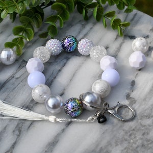 May include: White and silver beaded keychain with a leopard print charm and a white tassel.