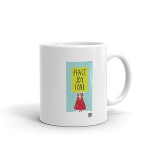 May include: White ceramic mug featuring a whimsical illustration. The design includes a figure holding a sign with the words "PEACE JOY LOVE" on a light blue background with falling snow. The mug has a curved handle.