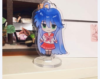 May include: A blue-haired anime character with green eyes wearing a red and white school uniform stands on a clear acrylic stand. The character is a chibi style figure.