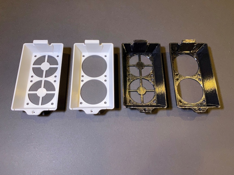 May include: Four rectangular, open-top containers with circular cutouts and gray inserts. Two are white, and two are black with gold accents. The containers have a series of small holes along the bottom edge.
