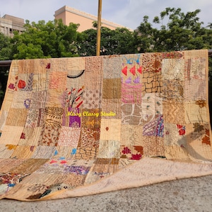 Könnte beinhalten: Ein Patchwork-Quilt mit einer Vielzahl von Mustern und Farben, darunter Beige, Braun, Rot und Lila. Der Quilt ist im Freien über ein Geländer drapiert, mit dem Text "Missy Classy Studio" sichtbar. Der Quilt scheint aus verschiedenen Stoffresten zu bestehen.