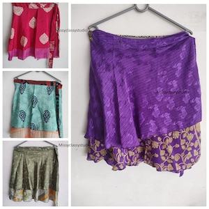 Könnte beinhalten: Drei verschiedene Stile von Wickelröcken aus recycelten Saris. Die Röcke sind in verschiedenen Farben und Mustern, darunter rosa, grün und lila. Jeder Rock hat ein einzigartiges Design und ist mit verschiedenen Stoffen geschichtet.