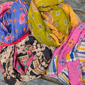 May include: Four colorful kantha quilts with intricate patterns in shades of pink, blue, green, and brown. The quilts are made of recycled saris and are hand-stitched with kantha embroidery.