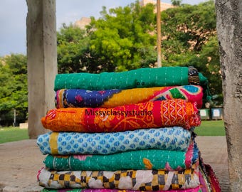 May include: A stack of colorful, patterned quilts. The quilts are folded and stacked, showcasing a variety of colors including green, blue, orange, and pink. The quilts appear to be handmade with visible stitching. The text "Missyclassystudio" is visible on one of the quilts.