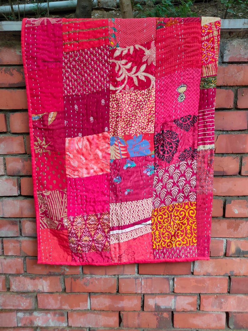 May include: A red patchwork quilt with a variety of floral and geometric patterns. The quilt is made of different fabrics and is hand-stitched.