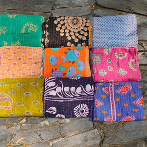 May include: Nine colorful kantha quilts with various patterns, including paisley, floral, and geometric designs. The quilts are made of recycled saris and are hand-stitched.