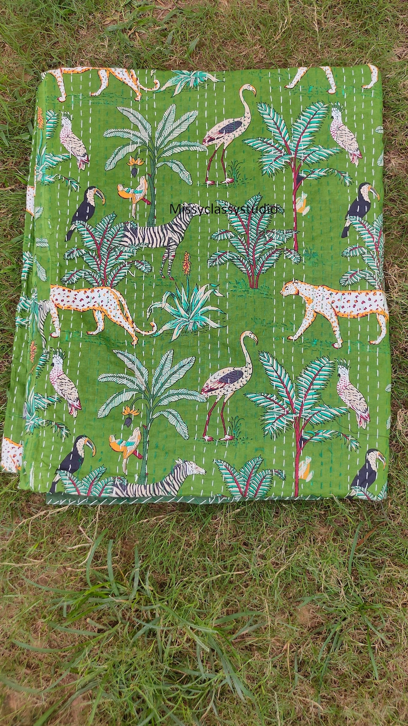 K&ouml;nnte beinhalten: Gr&uuml;ne Kantha-Steppdecke mit einem Muster aus Zebras, Leoparden, Flamingos, Tukanen und Palmen. Die Decke ist handgen&auml;ht und hat einen Vintage-Look.