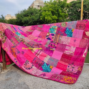 Peut inclure: Une courtepointe rose vif avec un patchwork de motifs et de textures vari&eacute;s. La courtepointe est drap&eacute;e sur une barre m&eacute;tallique, mettant en valeur son design complexe et ses variations de couleurs. Le texte "Missy Class Studio" est visible.