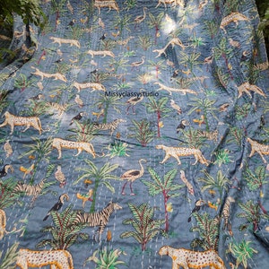 K&ouml;nnte beinhalten: Eine blaue Kantha-Steppdecke mit einem sich wiederholenden Muster aus Zebras, Leoparden, Flamingos und Palmen. Die Steppdecke ist handgen&auml;ht und hat einen Vintage-Look.