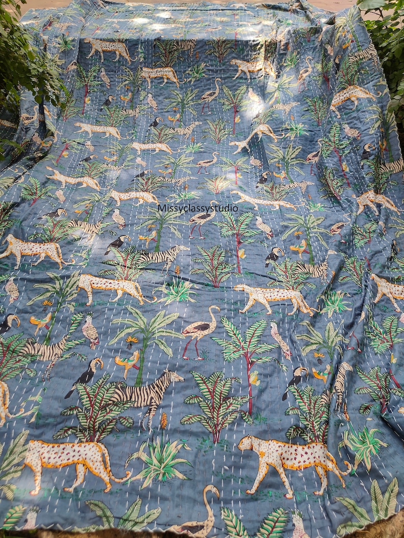 K&ouml;nnte beinhalten: Eine blaue Kantha-Steppdecke mit einem sich wiederholenden Muster aus Zebras, Leoparden, Flamingos und Palmen. Die Steppdecke ist handgen&auml;ht und hat einen Vintage-Look.