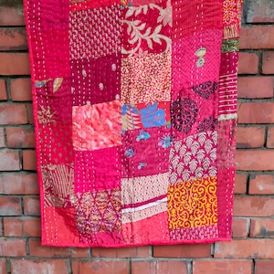 Può includere: Una trapunta rossa a patchwork con una varietà di motivi floreali e geometrici. La trapunta è realizzata con diversi tessuti ed è cucita a mano.