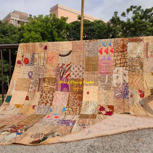 Könnte beinhalten: Ein Patchwork-Quilt mit verschiedenen Mustern und Farben, darunter Beige, Braun, Rot und Lila. Der Quilt ist im Freien über einem Geländer drapiert. Der Text "Missy Classy Studio" ist auf dem Quilt zu sehen.