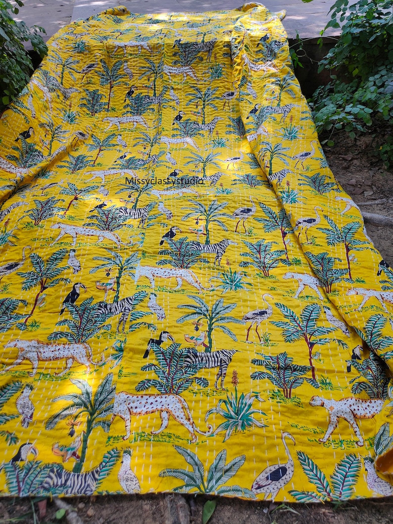 K&ouml;nnte beinhalten: Gelbe Kantha-Steppdecke mit einem Muster aus Zebras, Leoparden, V&ouml;geln und Palmen. Die Decke ist aus Baumwolle und hat ein handgesticktes Design.