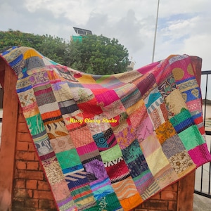 Könnte beinhalten: Eine Patchwork-Decke mit einer lebendigen Auswahl an bunten Stoffquadraten mit verschiedenen floralen, geometrischen und abstrakten Mustern. Das Textil ist mit sichtbaren Steppnähten versehen und zeigt den Text Missy Classy Studio.