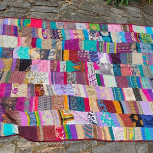 Könnte beinhalten: Ein farbenfroher Patchwork-Deckenbezug aus wiederverwendeten Stoffresten. Der Bezug besteht aus vielen verschiedenen Farben und Mustern, darunter florale, geometrische und Paisley-Designs. Der Bezug ist ein schönes Beispiel für Upcycling und Nachhaltigkeit.