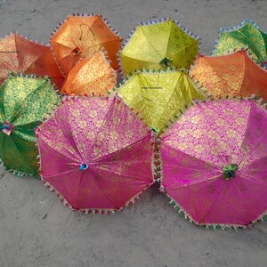 May include: A group of colorful umbrellas with gold accents and fringe trim. The umbrellas are made of fabric and have a variety of patterns.