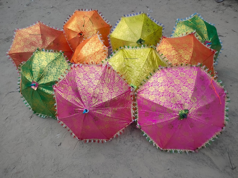 May include: A group of colorful umbrellas with gold accents and fringe trim. The umbrellas are made of fabric and have a variety of patterns.
