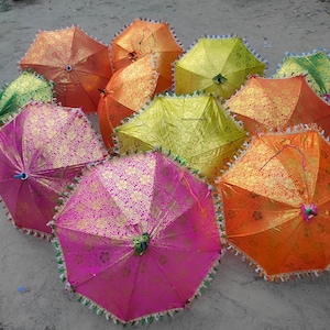 May include: A group of colorful, patterned umbrellas with fringed edges. The umbrellas are made of fabric and have a variety of colors, including pink, green, yellow, and orange.