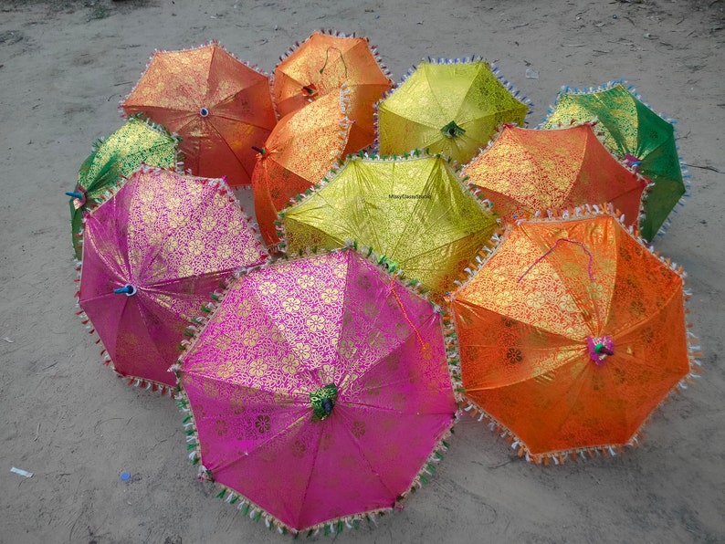 May include: A group of colorful, patterned umbrellas with fringed edges. The umbrellas are made of fabric and have a variety of colors, including pink, green, yellow, and orange.