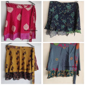 Pode incluir: Quatro saias envelope coloridas são exibidas. Uma é rosa vibrante com detalhes brancos e rosa. Outra é azul marinho com um padrão floral. Uma terceira é amarelo mostarda com um design repetido, e a última é azul com detalhes florais e laranja.