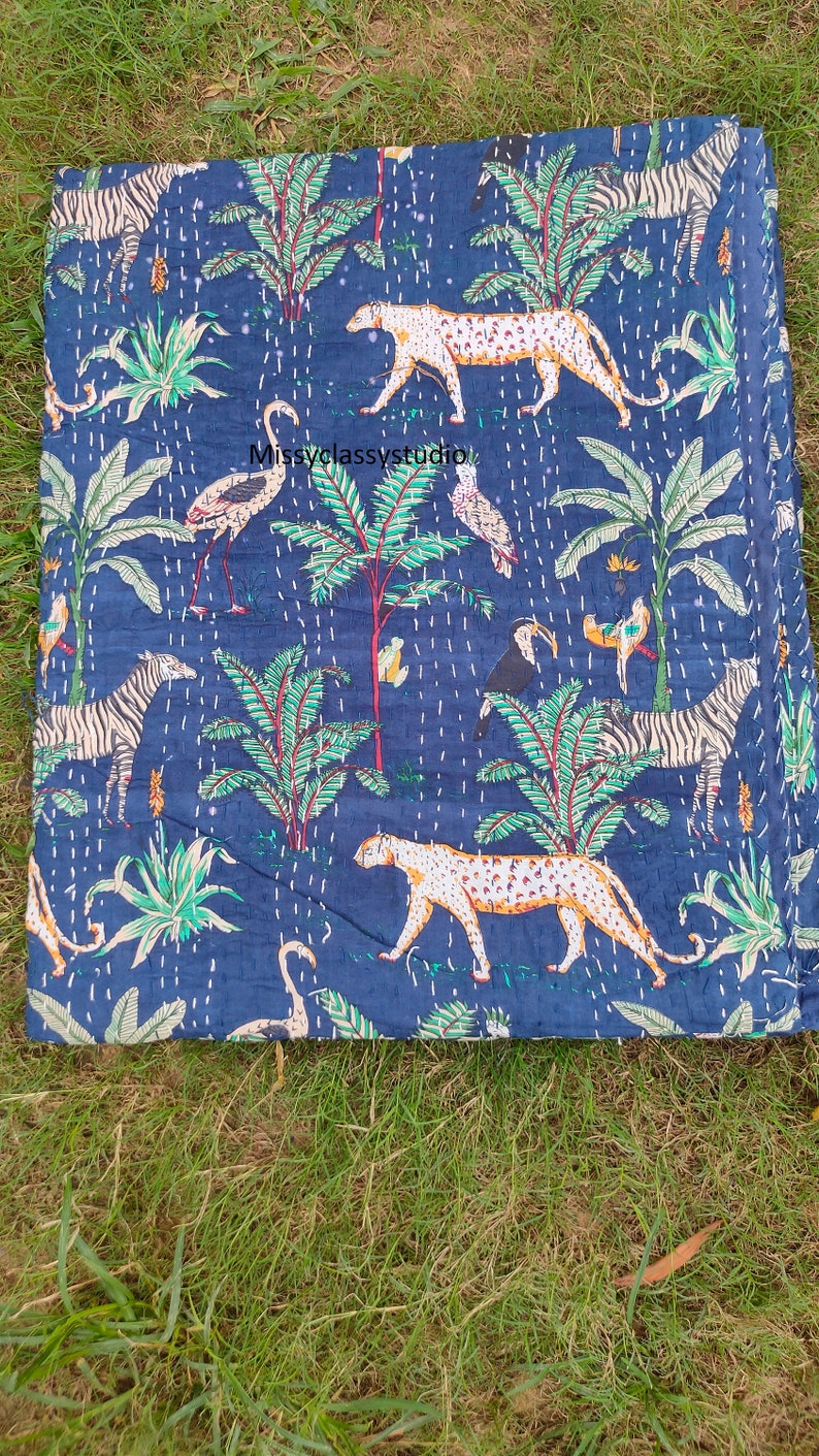 K&ouml;nnte beinhalten: Eine blaue Kantha-Steppdecke mit einem farbenfrohen Dschungel-Druck mit Zebras, Leoparden, V&ouml;geln und Palmen. Die Steppdecke ist aus Baumwolle und hat ein handgesticktes Design.
