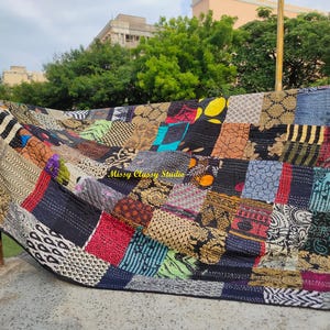 Könnte beinhalten: Eine große rechteckige Patchwork-Decke mit einer Vielzahl von Stoffquadraten in verschiedenen Mustern und Farben, darunter Schwarz, Gold, Rot, Blau und Grün. Die Decke zeigt sichtbare Kantha-Nähte und den Text Missy Classy Studio.