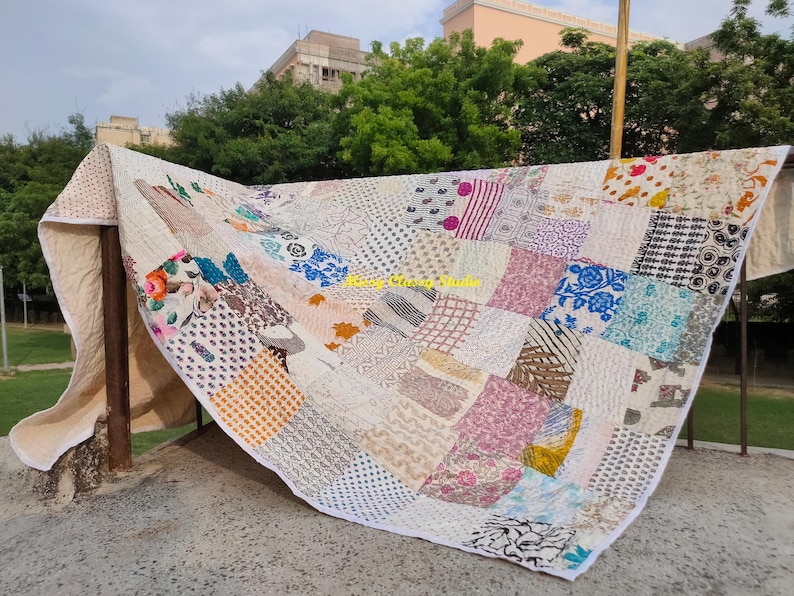 Peut inclure: Une courtepointe patchwork avec une vari&eacute;t&eacute; de motifs et de couleurs, notamment des motifs floraux, g&eacute;om&eacute;triques et abstraits. La courtepointe est compos&eacute;e de carr&eacute;s de tissu de diff&eacute;rentes couleurs, notamment rose, bleu, blanc et marron. La courtepointe est drap&eacute;e sur une structure m&eacute;tallique.