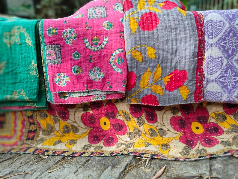 Puede incluir: Una pila de cuatro colchas kantha coloridas con patrones florales y geom&eacute;tricos. Las colchas est&aacute;n hechas de algod&oacute;n y est&aacute;n cosidas a mano. Son perfectas para agregar un toque de estilo bohemio a tu hogar.