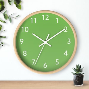 May include: A green clock with white numbers and hands on a white wall. The clock has a wooden frame.