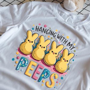 May include: White t-shirt with a graphic of yellow marshmallow peeps and the text "Hanging with my peeps".