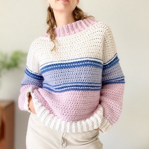 May include: A striped crochet sweater with pink, white and blue stripes. The sweater has a relaxed fit and long sleeves.