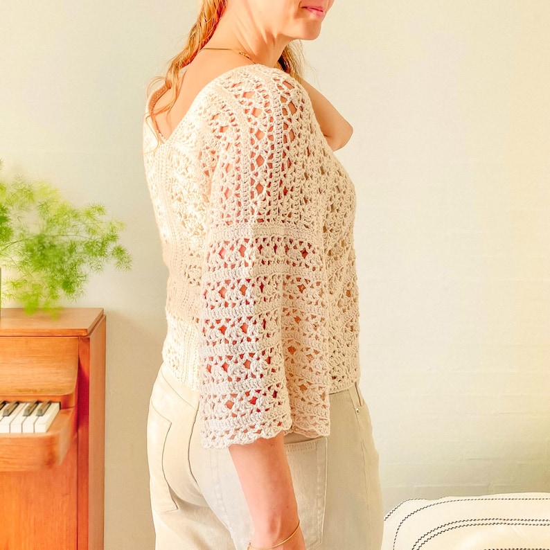 May include: A white crochet top with a loose, flowy fit and a square neckline. The top has a delicate, lacy pattern and is perfect for a summer day.