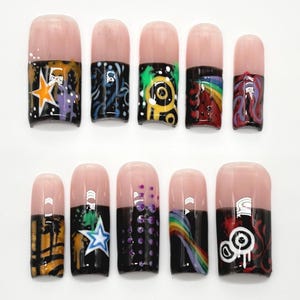 May include: A set of ten artificial nails with a light pink base and black tips. Each nail features unique abstract art in various colors, including stars, swirls, and rainbow designs. The nails are arranged on a white surface.