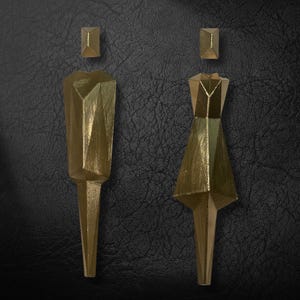 May include: Two gold-coloured geometric figures, one with a skirt and the other with a rectangular top, on a black textured background.