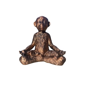 Könnte beinhalten: Eine bronzefarbene Affenfigur, die in meditativer Yoga-Pose mit geschlossenen Augen sitzt.